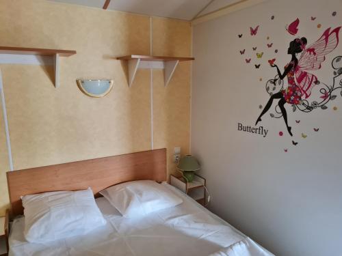 um quarto com uma cama com um adesivo de borboleta na parede em Mobil home sur camping 4 étoiles CAP SOLEIL St Denis d'Oléron em La Bétaudière