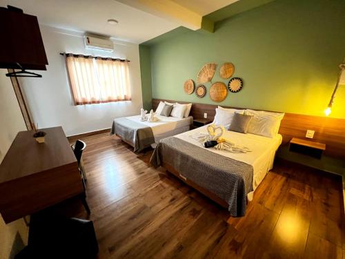 a hotel room with two beds and a table at Hotel Fazenda Vale da Cachoeira in Serra Negra