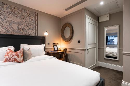 a bedroom with a large bed and a mirror at King Street Townhouse in Manchester