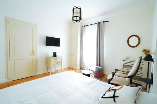 a bedroom with a large white bed and a chair at B&B La Maison Galiène in Bordeaux