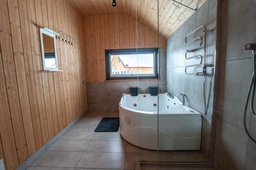 La grande salle de bains est pourvue d'une baignoire et d'une fenêtre. dans l'établissement Sodybos kompleksas - ECO Resort Trakai, à Antakalnis