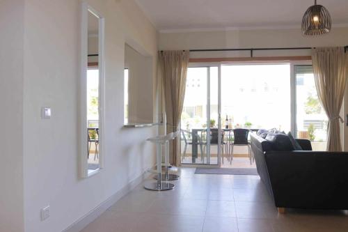 a living room with a couch and a view of a patio at Apartamento Canada Formosa Cabanas Beach by Your Home Algarve in Cabanas de Tavira