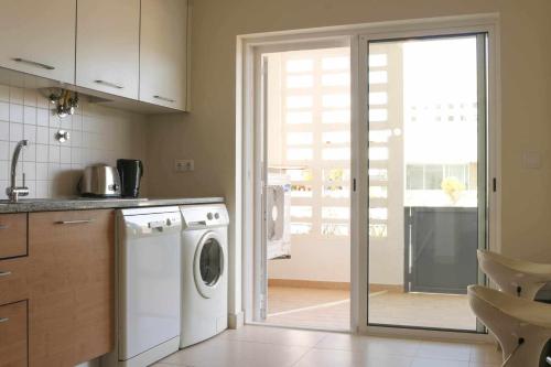 a kitchen with a washing machine and a sliding glass door at Apartamento Canada Formosa Cabanas Beach by Your Home Algarve in Cabanas de Tavira