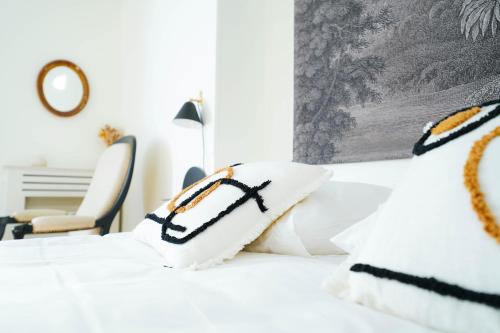 a white bed with black and white pillows on it at B&B La Maison Galiène in Bordeaux