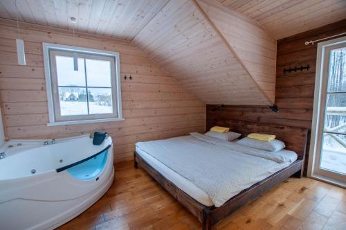 a bedroom with a bed and a bath tub at Sodybos kompleksas - ECO Resort Trakai in Antakalnis