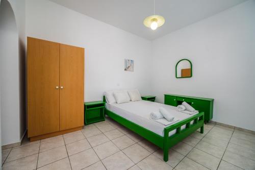 a bedroom with a green bed and a wooden cabinet at Ancient Thera Apartments in Kamari