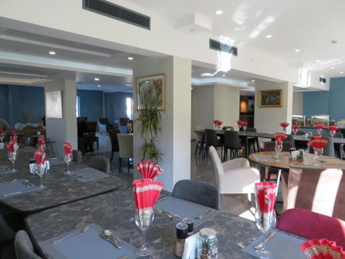 a restaurant with tables and chairs with red flowers on them at Hotel Sun in North Nicosia