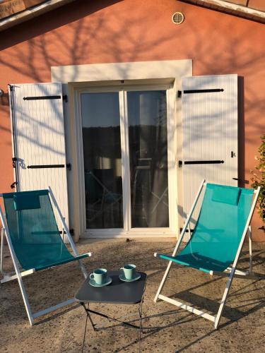 two chairs and a table in front of a door at Aux couleurs d’Ardèche in Vallon-Pont-dʼArc