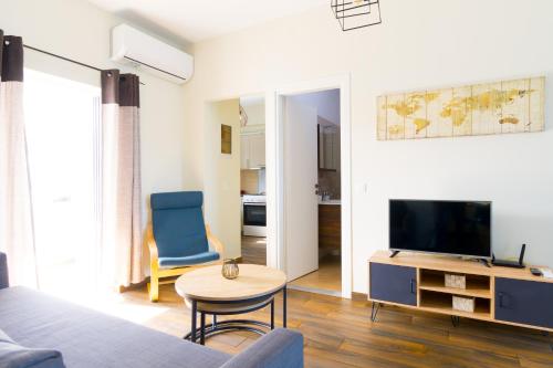 een woonkamer met een tv en een blauwe stoel bij Elounda Harmony Sea front apartment in Elounda