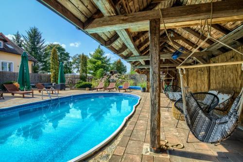 an outdoor swimming pool with a wooden roof and chairs at Oaza Mazurska - Willa Lasek in Piecki