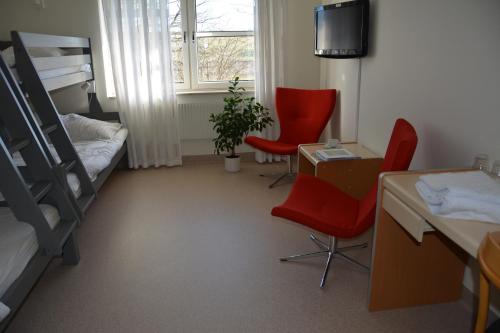 Pokój z 2 czerwonymi krzesłami i łóżkiem piętrowym w obiekcie Katrinebergs Folkhögskola B&B w mieście Vessigebro
