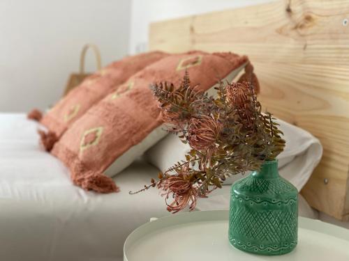 a green vase with flowers on a table next to pillows at Housingleon- Camino de Santiago by Bike I y II in León