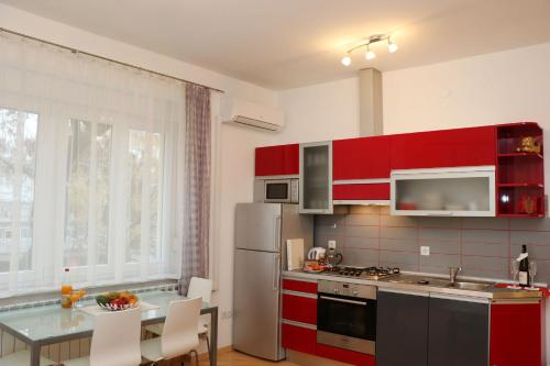 a kitchen with red cabinets and a table with chairs at Apartment Elena 1, Zagreb City with garage in Zagreb