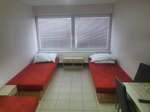 Pokój z 2 czerwonymi łóżkami i oknem w obiekcie ubytovanie FRENAT w mieście Kúty