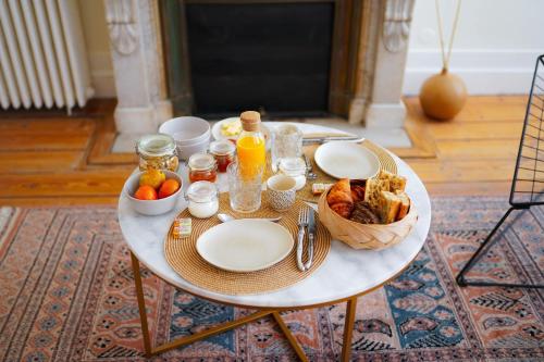 a table with plates of food and a basket of fruit at B&B La Maison Galiène in Bordeaux