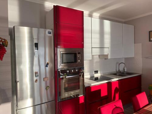 uma cozinha com armários vermelhos e um frigorífico de aço inoxidável em SEAFRONT em Portoferraio