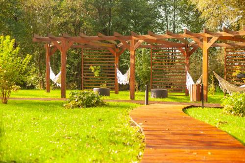 a wooden path in a park with a wooden pergola at Baltic Natur Park - Holiday Resort in Niechorze