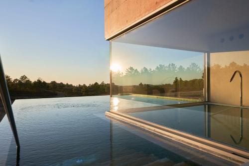 a glass house with a view of the water at Praia do Canal Nature Retreat - Small Luxury Hotels of the World in Aljezur