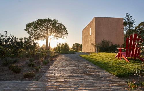 a brick path with two red chairs and a building at Praia do Canal Nature Retreat - Small Luxury Hotels of the World in Aljezur