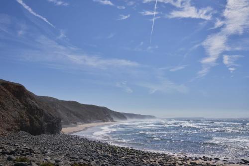 a beach with a rocky shoreline and the ocean at Praia do Canal Nature Retreat - Small Luxury Hotels of the World in Aljezur