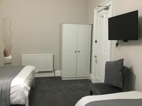 エディンバラにあるAmaryllis Guest Houseのベッドルーム1室(ベッド2台、キャビネット、椅子付)