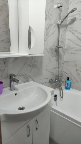 a white bathroom with a sink and a shower at Василя Стуса 10/77 City Rooms in Bila Tserkva