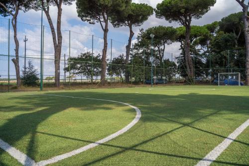 a tennis court with a net and some trees at ISOLA VERDE Camping Village in Nettuno