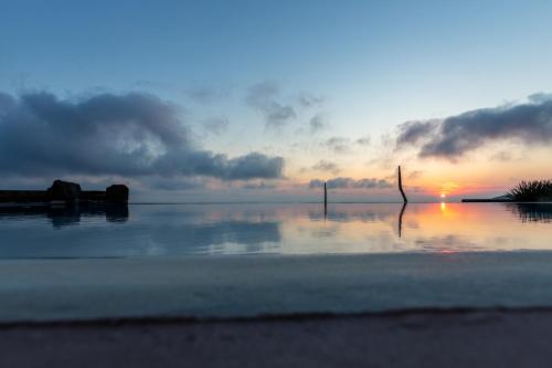 a sunset over a body of water with a pole in the water at Pantelleria Dream Resort in Pantelleria