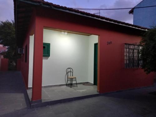 a chair sits in the doorway of a red and white building at Casa Aconchegante in São Sebastião