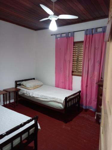 a bedroom with two beds and pink curtains at Casa Aconchegante in São Sebastião
