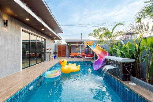 a swimming pool with two rubber ducks in a house at หมุนเงินหมุนทองพูลวิลล่า Mhunngen Mhunthong Pool Villa in Cha Am