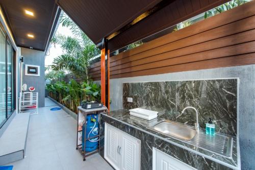 an outdoor kitchen with a sink and a counter at หมุนเงินหมุนทองพูลวิลล่า Mhunngen Mhunthong Pool Villa in Cha Am