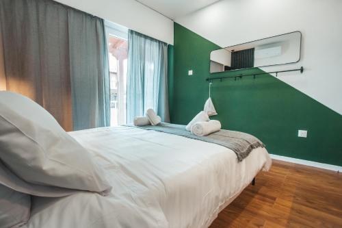 a bedroom with a large bed with a green wall at The Green Apartment in Larnaca