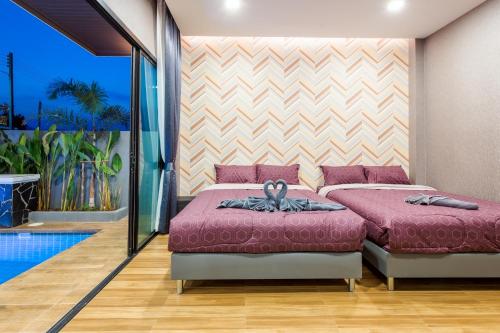 a bedroom with two beds and a swimming pool at หมุนเงินหมุนทองพูลวิลล่า Mhunngen Mhunthong Pool Villa in Cha Am