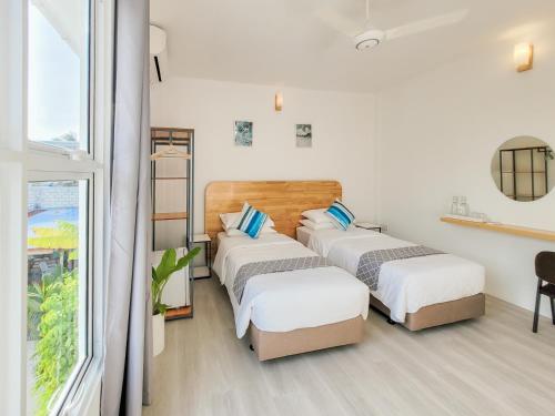 three beds in a room with a window at Hudhufas Villa in Thoddoo