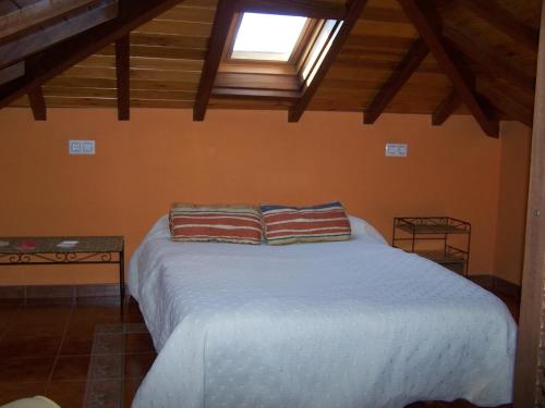 a bedroom with a white bed with a window at Casa El Trabeseo in San Martín de Luiña