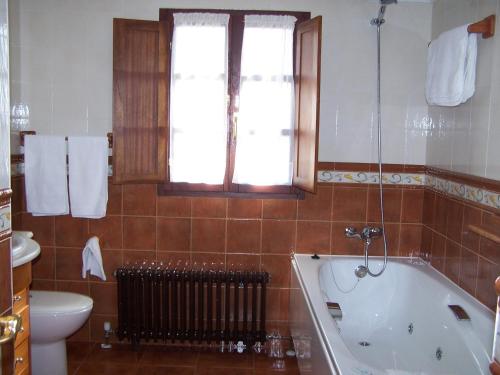 baño con bañera, aseo y ventana en Casa El Trabeseo, en San Martín de Luiña
