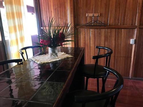a table with chairs and a vase of flowers on it at Hotel Green Mountain turrialba in Turrialba