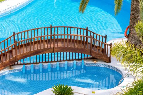 uma piscina com uma ponte de madeira sobre uma piscina em Mònica Hotel em Cambrils
