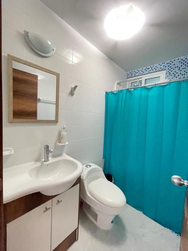 baño con aseo blanco y cortina de ducha azul en Departamento vista al mar 2D, en Tonsupa