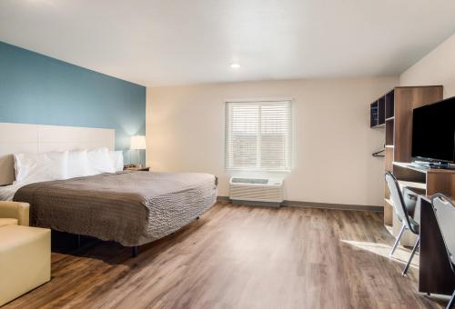 a bedroom with a bed and a flat screen tv at WoodSpring Suites Thornton-North Denver in Thornton