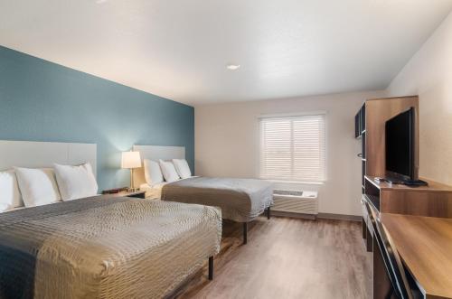 a hotel room with two beds and a flat screen tv at WoodSpring Suites Thornton-North Denver in Thornton