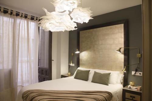 a bedroom with a large bed and a chandelier at Apartamento Palacio Descalzos in Tudela