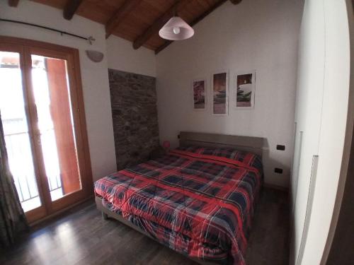 Un dormitorio con una cama con edredón y una ventana. en La casa del Ciodo, en Colico