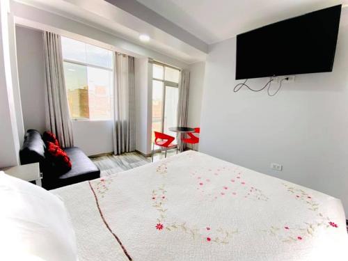 1 dormitorio con 1 cama y TV en la pared en Hostal D' Rosas, en Tacna