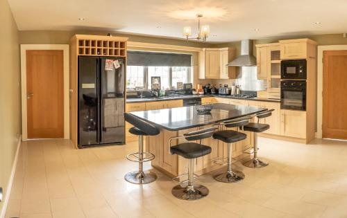 a kitchen with a black refrigerator and bar stools at Grianan Luxury Lodge by Wild Atlantic Wanderer in Claragh