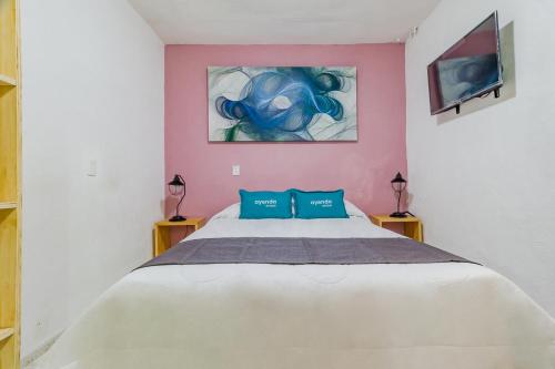 a bedroom with a large white bed with blue pillows at Ayenda Los Colorines de Coyoacán in Mexico City