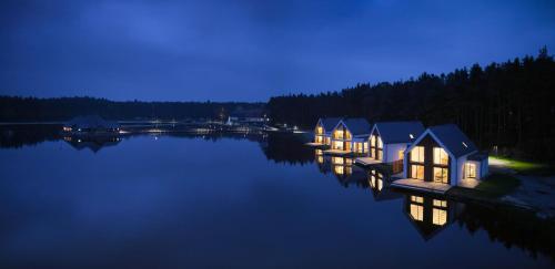 una fila de cabañas en un lago por la noche en Dębowy Dwór en Ruda Różaniecka