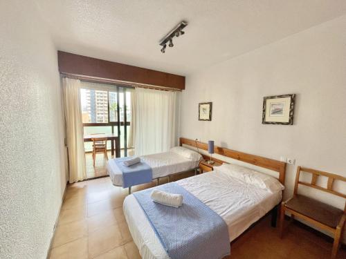 a bedroom with two beds and a chair and a window at Albaida Park Apartment in Benidorm