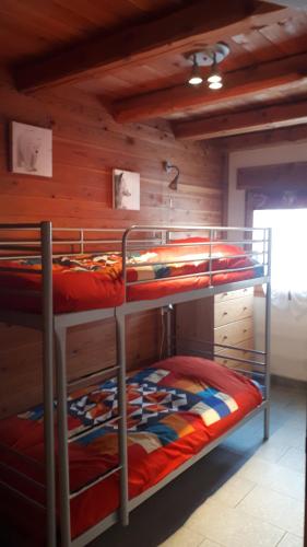 Ce lit se trouve dans un dortoir doté de 2 lits superposés et de murs en bois. dans l'établissement Appartement 58m2 avec jardin & terrasse dans chalet, à Montgenèvre